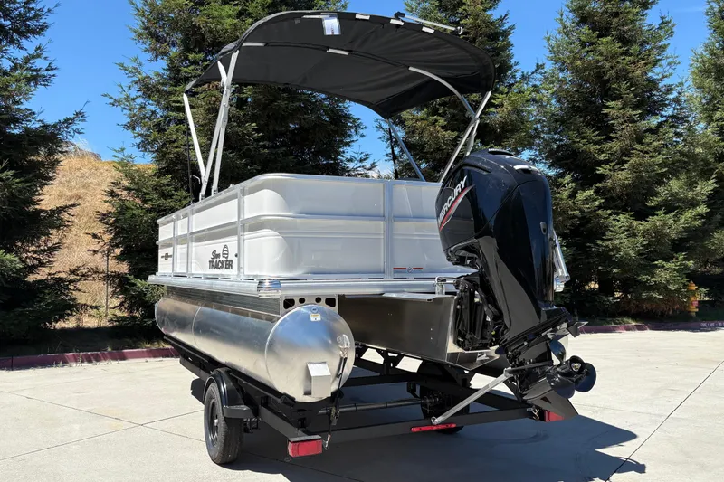 Slide: The Image of 2026 Sun Tracker Party Barge 18 DLX pontoon boat with Mercury outboard motor, parked outdoors. - 10