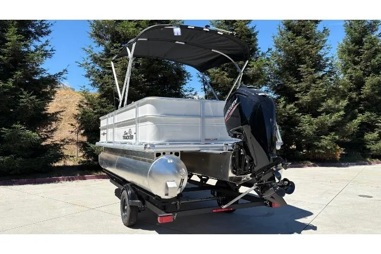 Slide: The Image of 2026 Sun Tracker Party Barge 18 DLX pontoon boat with canopy, parked outdoors. - 12