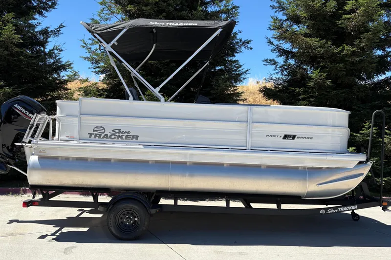 The Image of 2026 Sun Tracker Party Barge 18 DLX pontoon boat on trailer, parked outdoors. - 0