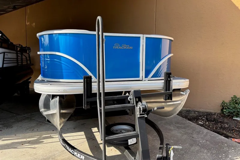 Slide: The Image of 2026 Sun Tracker Party Barge 16 DLX pontoon boat in storage, featuring a vibrant blue exterior. - 5
