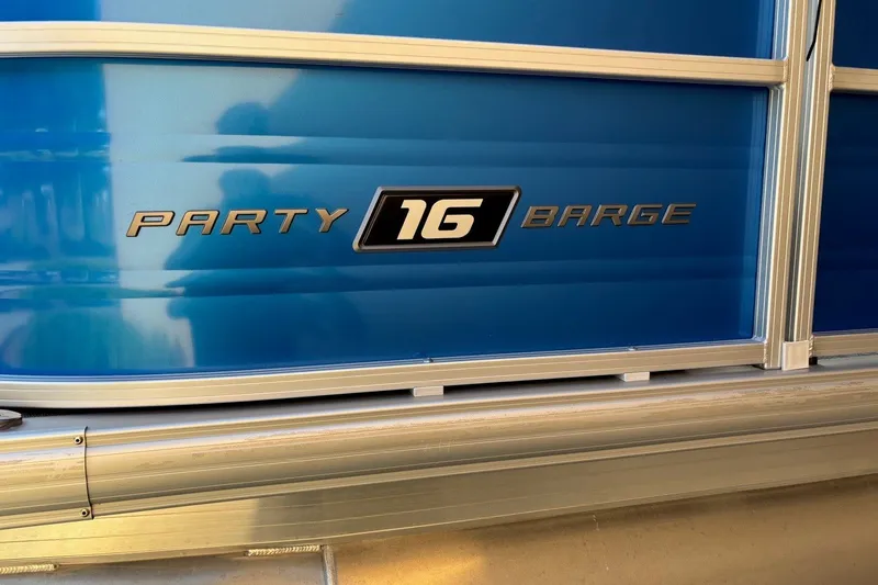 Slide: The Image of 2026 Sun Tracker Party Barge 16 DLX, blue exterior with logo detail. - 8