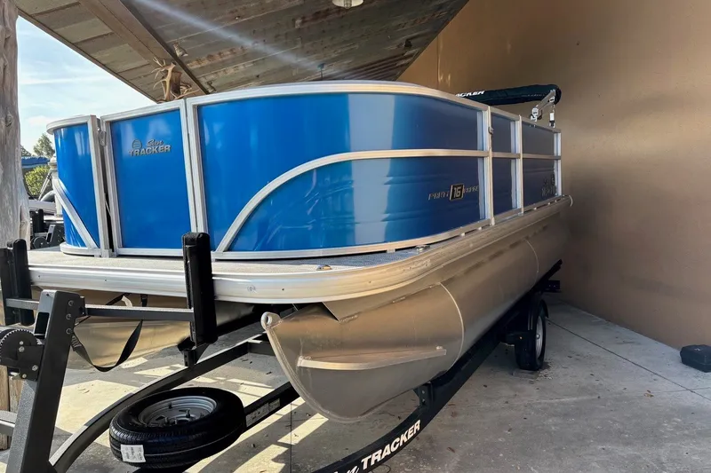 Slide: The Image of 2026 Sun Tracker Party Barge 16 DLX pontoon boat on trailer, under shelter. - 13