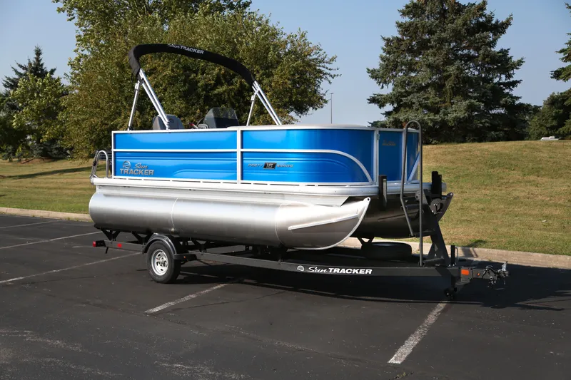 The Image of 2026 Sun Tracker Party Barge 16 DLX pontoon boat on trailer, parked outdoors. - 0