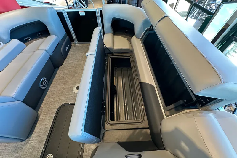 Slide: The Image of 2026 Sun Tracker Party Barge 22 XP3 interior with open storage compartment and cushioned seating. - 19