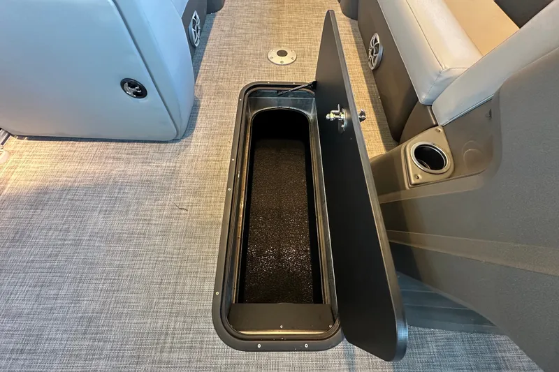 Slide: The Image of 2026 Sun Tracker Party Barge 22 XP3 interior storage compartment with open lid on carpeted floor. - 17