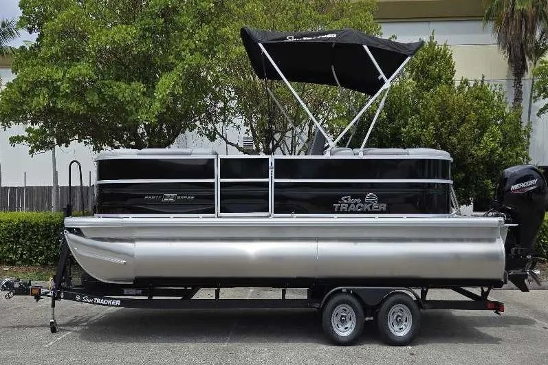 The Image of 2026 Sun Tracker Party Barge 22 DLX pontoon boat on trailer, parked outdoors. - 0