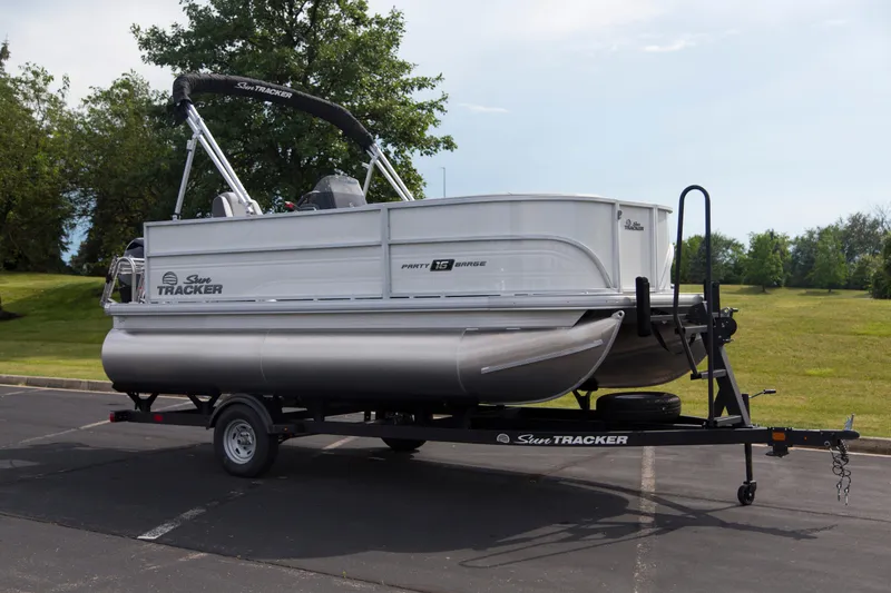 The Image of 2026 Sun Tracker Party Barge 16 DLX pontoon boat on trailer, parked outdoors. - 0