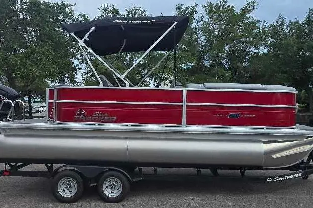 The Image of 2026 Sun Tracker Party Barge 20 DLX pontoon boat on trailer, red exterior, parked outdoors. - 0