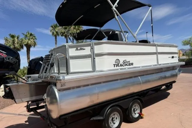 Slide: The Image of 2026 Sun Tracker Party Barge 20 DLX pontoon boat on trailer, under sunny skies. - 1