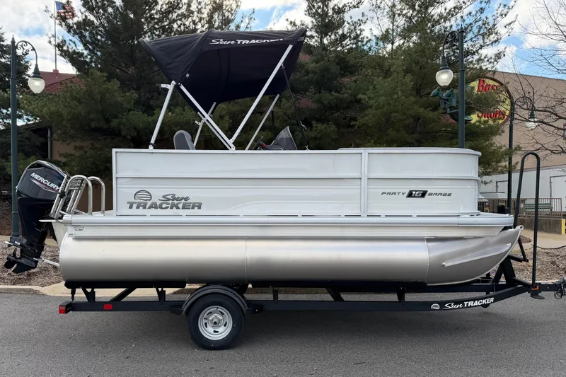 The Image of 2026 Sun Tracker Party Barge 16 DLX pontoon boat on trailer, parked outdoors. - 0
