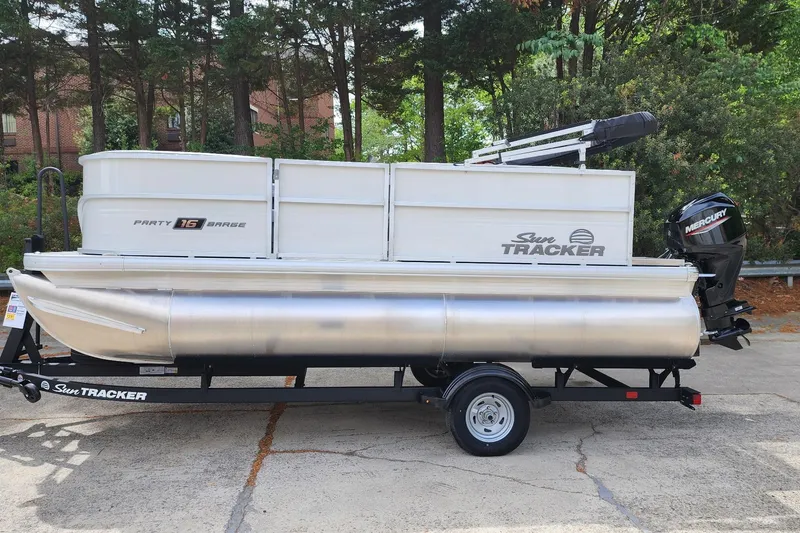 The Image of 2026 Sun Tracker Party Barge 16 DLX pontoon boat on trailer, parked outdoors. - 0