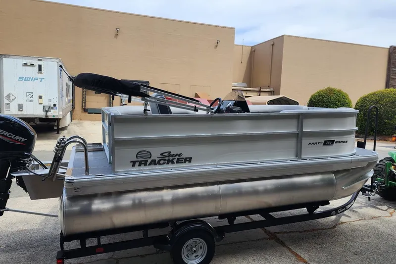 Slide: The Image of 2026 Sun Tracker Party Barge 16 DLX pontoon boat on trailer, parked outdoors. - 3