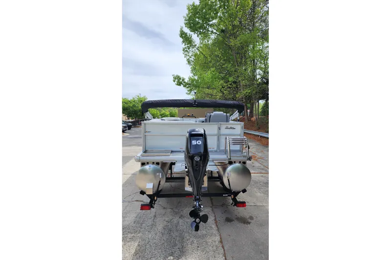 Slide: The Image of 2026 Sun Tracker Party Barge 16 DLX pontoon boat with outboard motor, parked outdoors. - 4