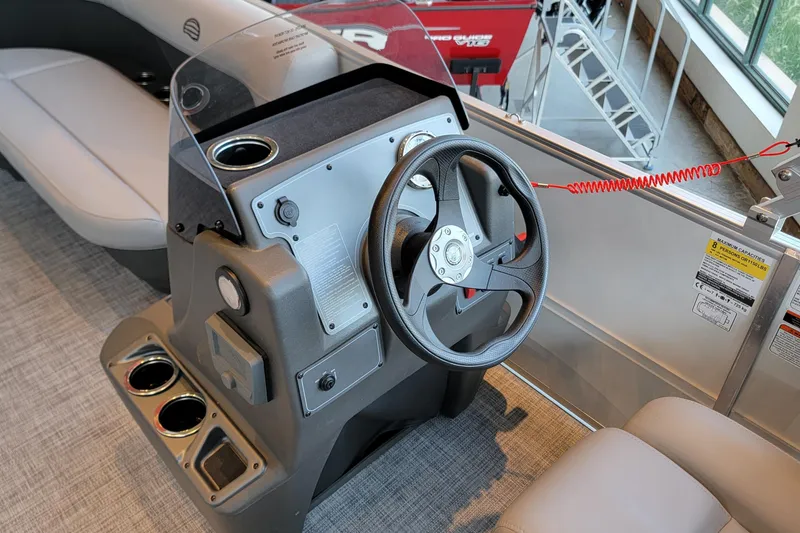 Slide: The Image of 2026 Sun Tracker Party Barge 16 DLX steering console with cup holders and safety features. - 3