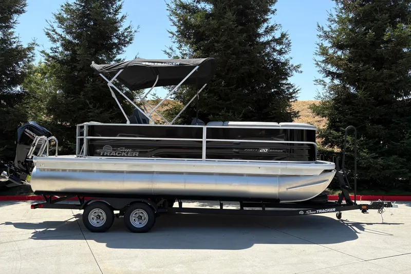 The Image of 2026 Sun Tracker Party Barge 20 DLX pontoon boat on trailer, parked outdoors. - 0