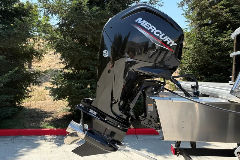 Slide: The Image of 2026 Sun Tracker Party Barge 20 DLX with Mercury outboard motor, parked near trees. - 14