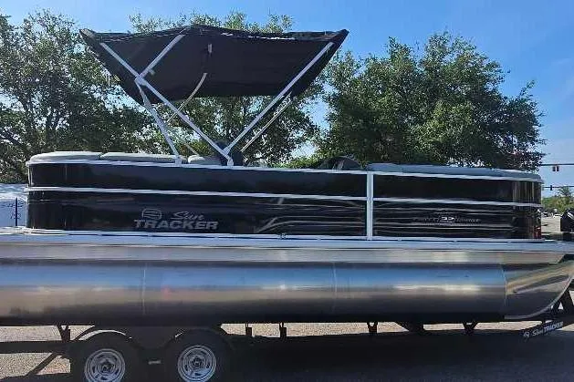 Slide: The Image of 2026 Sun Tracker Party Barge 22 XP3 pontoon boat on trailer, parked outdoors. - 2