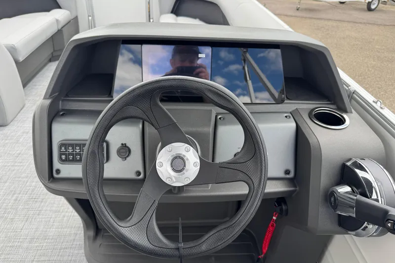 Slide: The Image of Steering console of 2026 Sun Tracker Party Barge 16 DLX with modern controls and cup holder. - 11