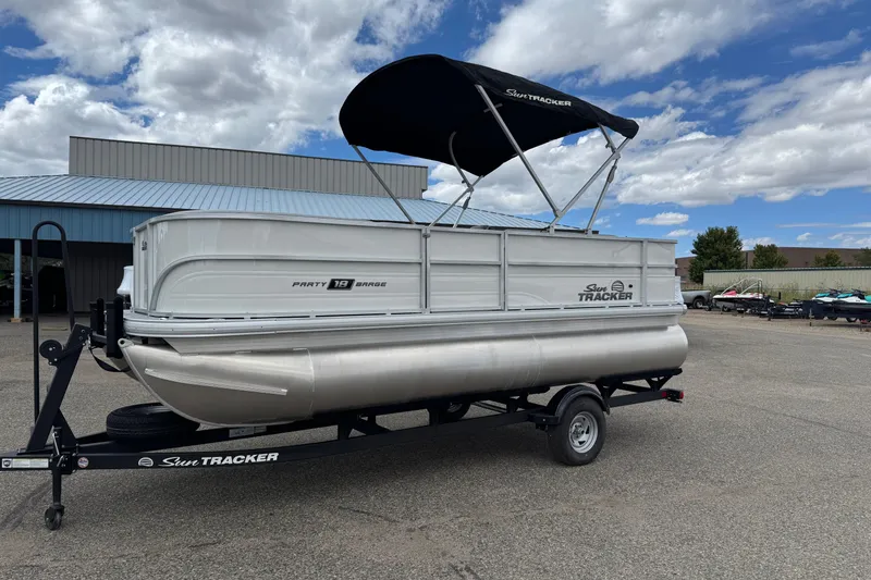 Slide: The Image of 2026 Sun Tracker Party Barge 16 DLX pontoon boat on trailer, under blue sky. - 2