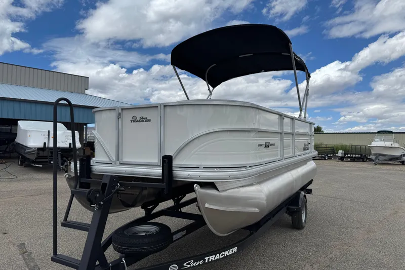 Slide: The Image of 2026 Sun Tracker Party Barge 16 DLX pontoon boat on trailer under blue sky. - 3