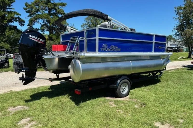 Slide: The Image of 2026 Sun Tracker Party Barge 16 DLX pontoon boat on trailer, parked on grass. - 5