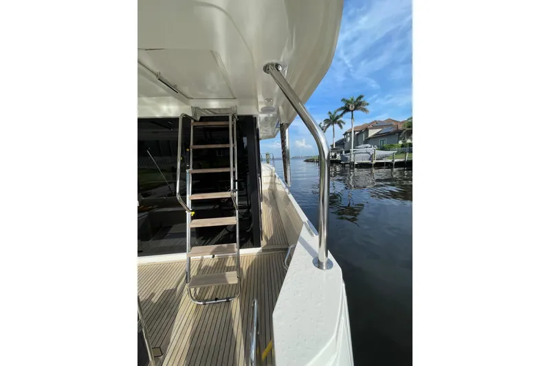 Slide: The Image of 2025 Beneteau Swift Trawler 41 Fly deck with ladder, overlooking waterfront homes and palm trees. - 13
