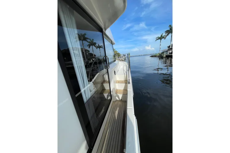 Slide: The Image of 2025 Beneteau Swift Trawler 41 Fly, side deck view with palm trees and water. - 14
