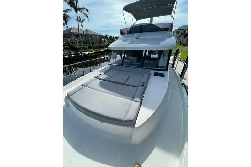 Slide: The Image of 2025 Beneteau Swift Trawler 41 Fly with sun deck, docked near waterfront homes. - 15