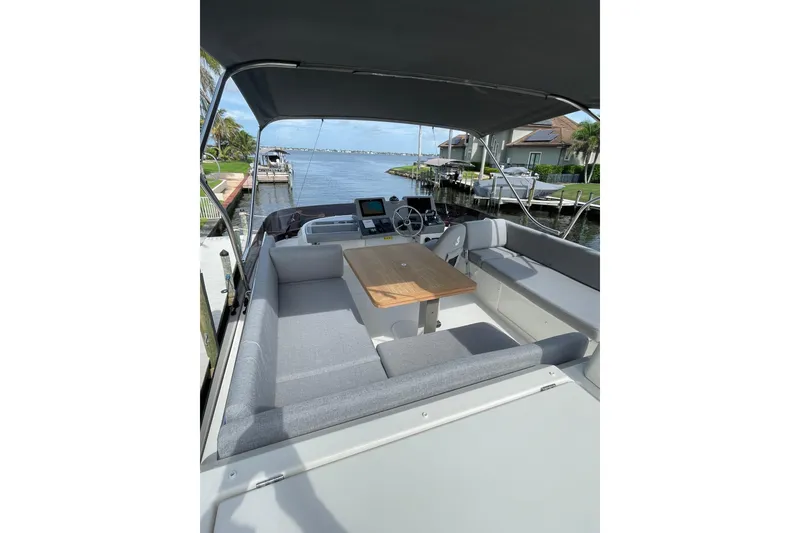 Slide: The Image of 2025 Beneteau Swift Trawler 41 Fly, spacious deck with seating and table, docked by waterfront. - 22