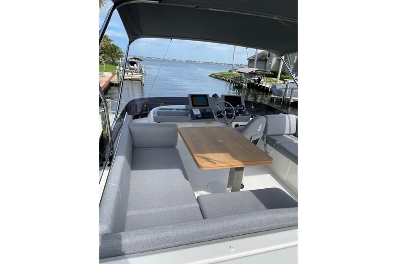 Slide: The Image of 2025 Beneteau Swift Trawler 41 Flybridge with seating and table, overlooking a serene waterfront. - 23