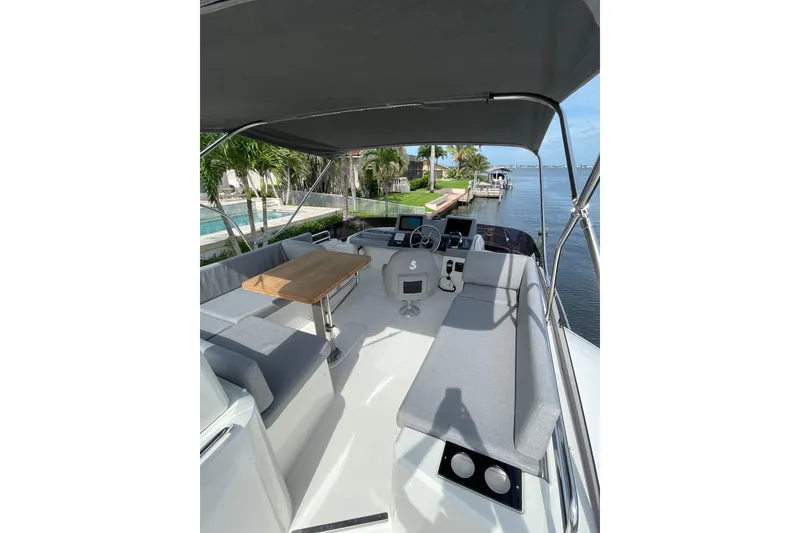 Slide: The Image of 2025 Beneteau Swift Trawler 41 Fly, spacious flybridge with seating and table, dockside view. - 25