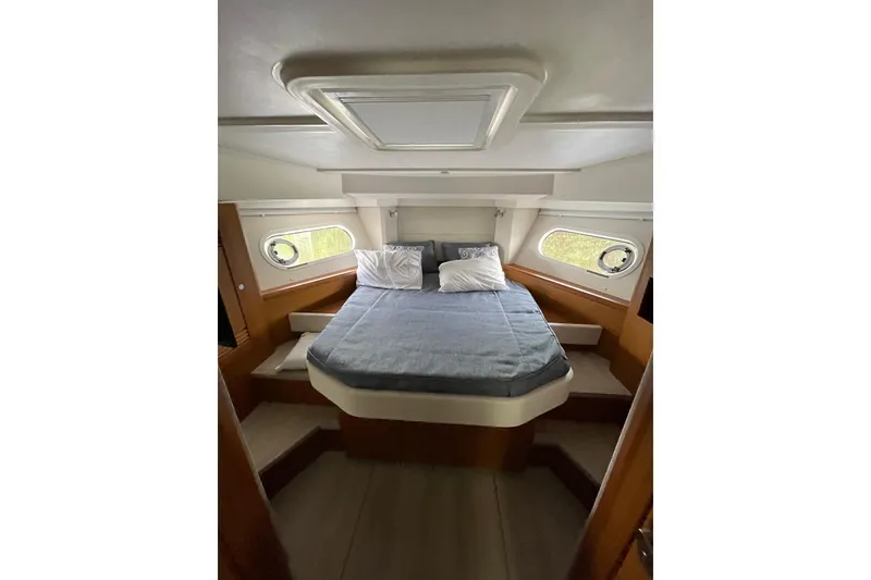Slide: The Image of 2025 Beneteau Swift Trawler 41 Fly cabin with bed, portholes, and wooden interior. - 30