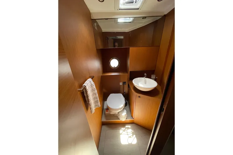 Slide: The Image of 2025 Beneteau Swift Trawler 41 Fly bathroom with wood finish, sink, and porthole window. - 32