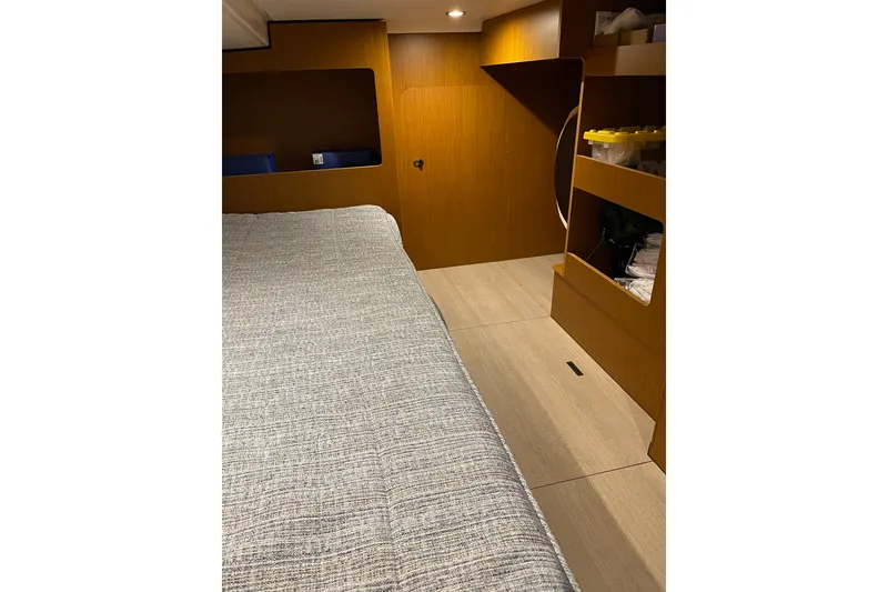 Slide: The Image of 2025 Beneteau Swift Trawler 41 Fly cabin interior with bed and wooden storage shelves. - 35