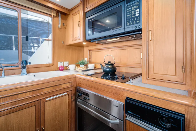 Slide: The Image of Galley kitchen in 2001 Fleming 55 Pilothouse yacht with wooden cabinetry and modern appliances. - 15