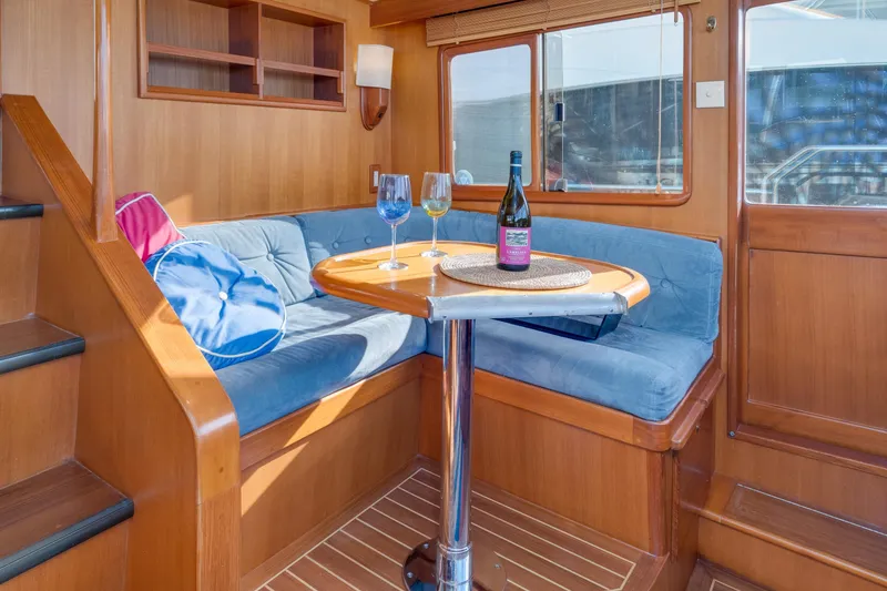 Slide: The Image of Cozy interior of 2001 Fleming 55 Pilothouse with blue seating and wine on table. - 22