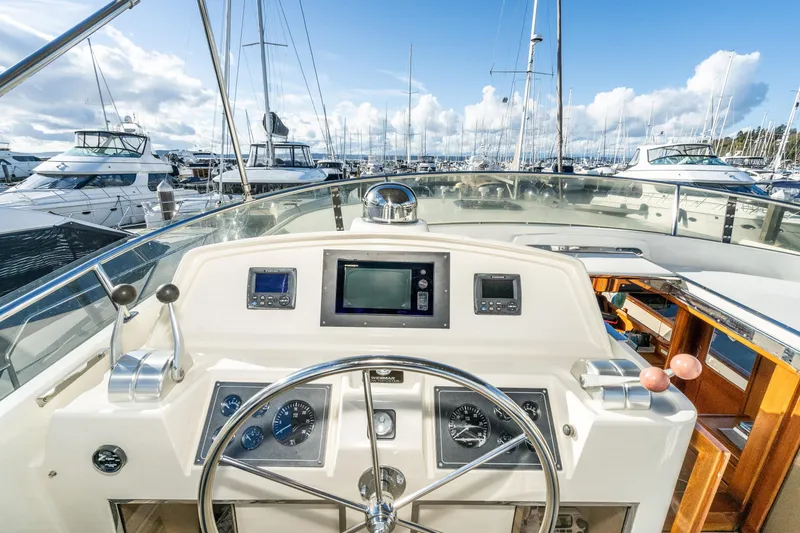 Slide: The Image of Pilothouse of 2001 Fleming 55 yacht, featuring navigation instruments and steering wheel in a marina. - 27