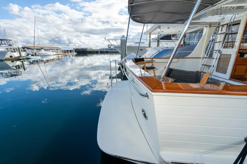 Slide: The Image of 2001 Fleming 55 Pilothouse yacht docked at a serene marina, reflecting on calm water. - 4