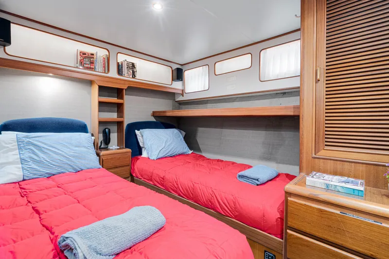 Slide: The Image of Cozy twin cabin in 2001 Fleming 55 Pilothouse yacht with red bedding and wooden accents. - 44