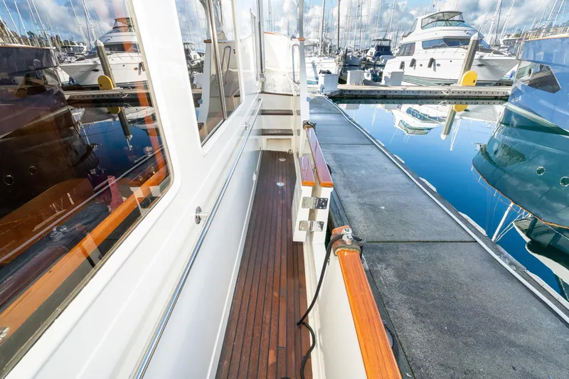 Slide: The Image of Fleming 55 Pilothouse yacht docked, showcasing sleek design and wooden deck, 2001 model. - 56