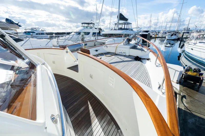 Slide: The Image of 2001 Fleming 55 Pilothouse yacht docked in a marina, showcasing elegant wooden deck and railings. - 58