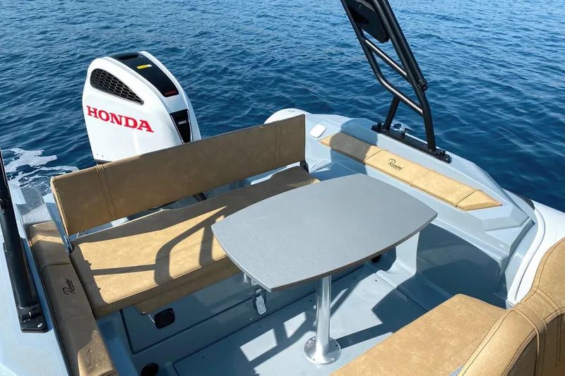 Slide: The Image of 2023 Ranieri CAYMAN 26 SPORT boat with Honda engine, featuring seating and table on calm water. - 13