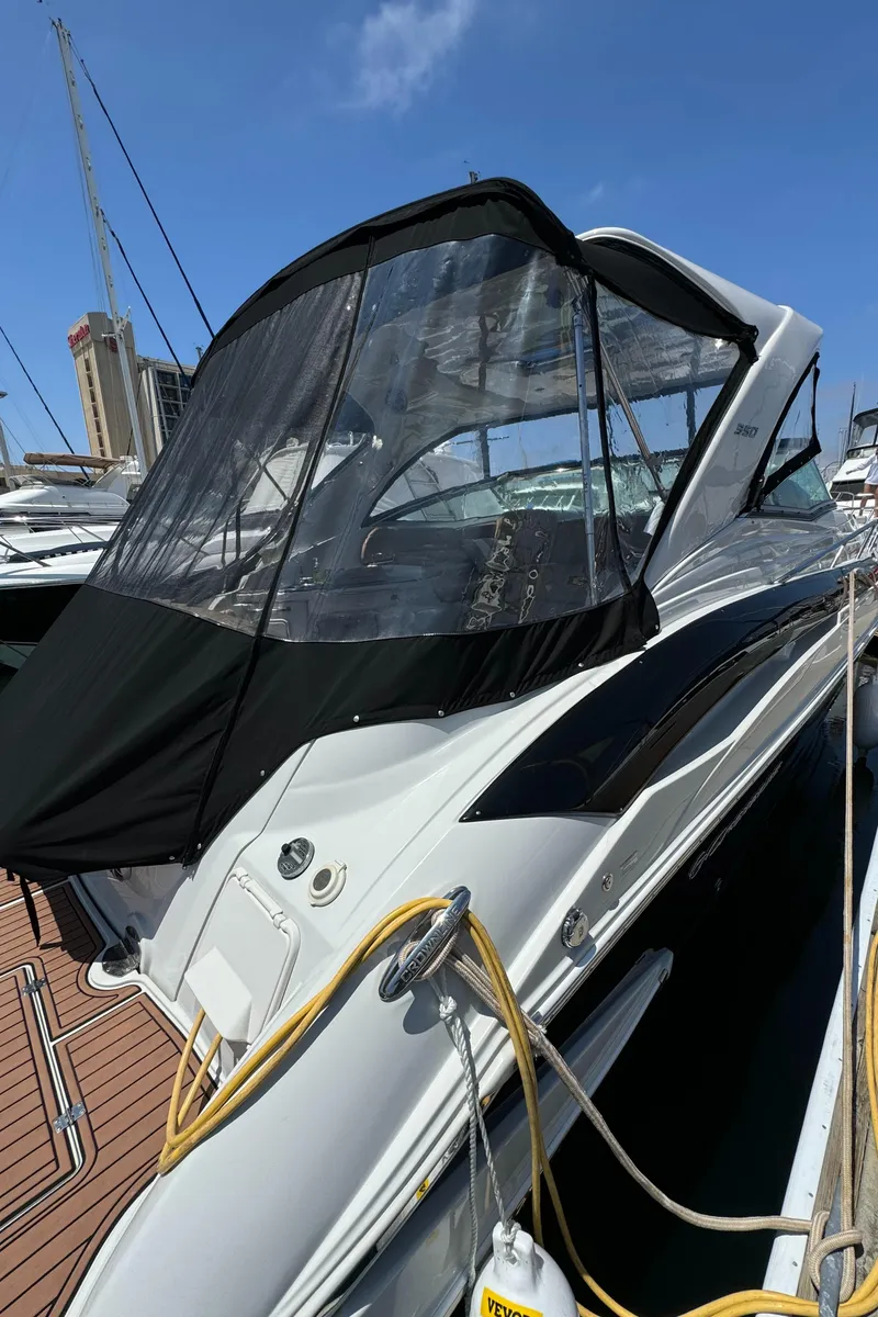 Slide: The Image of 2018 Crownline 350 SY yacht docked, featuring sleek design and modern canopy under clear blue sky. - 14