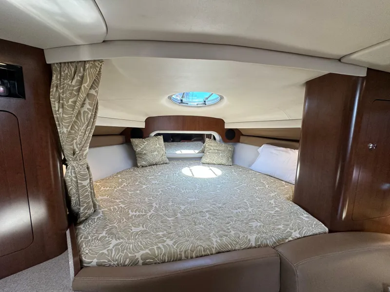 Slide: The Image of 2018 Crownline 350 SY cabin interior with bed, wood paneling, and round window. - 47