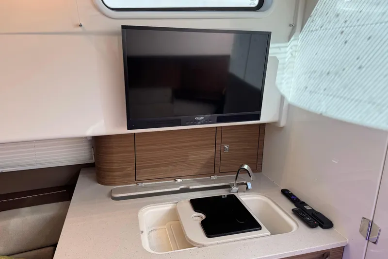 Slide: The Image of 2020 Boston Whaler 420 Outrage interior with TV, sink, and remote controls. - 13