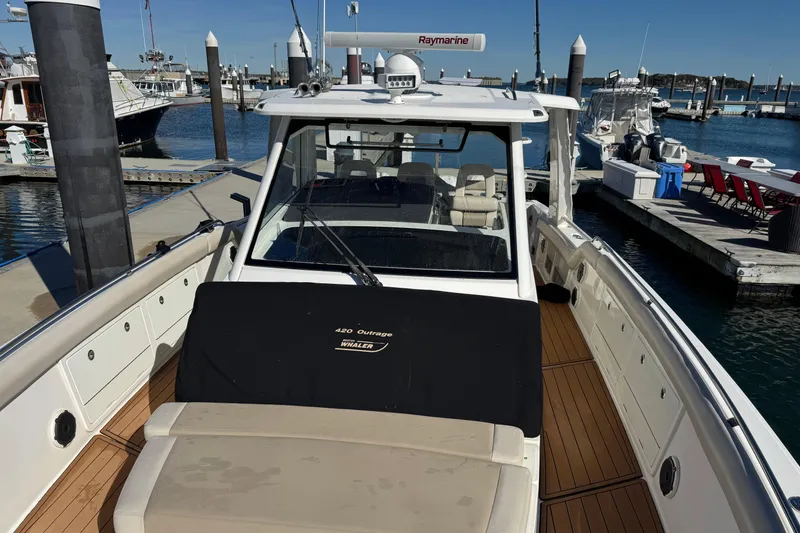 Slide: The Image of 2020 Boston Whaler 420 Outrage docked at marina, showcasing spacious deck and sleek design. - 17