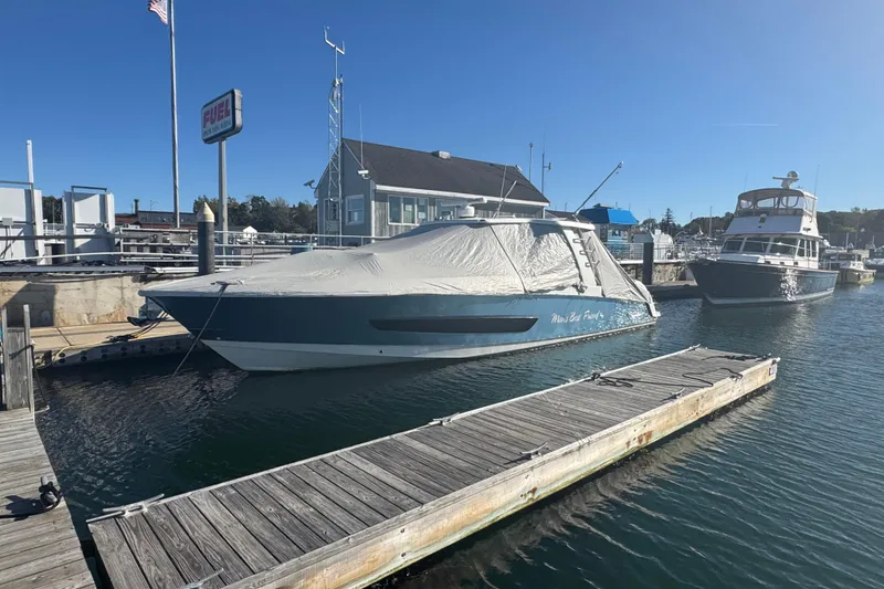 Slide: The Image of 2020 Boston Whaler 420 Outrage docked, covered, in a marina under clear blue sky. - 8