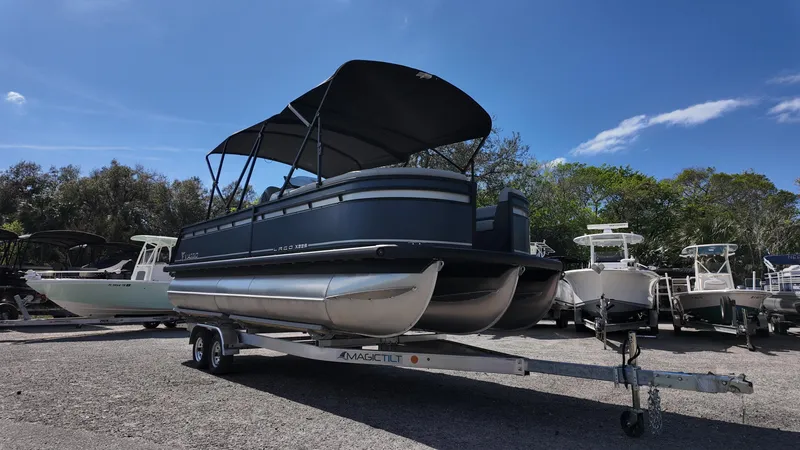 Slide: The Image of 2025 Viaggio X22S pontoon boat on trailer, parked outdoors under clear blue sky. - 3