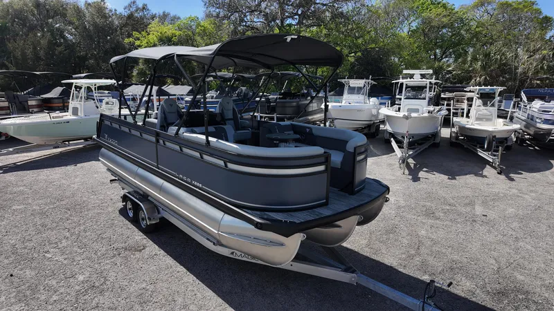 Slide: The Image of 2025 Viaggio X22S pontoon boat on trailer, surrounded by other boats in a sunny outdoor setting. - 4