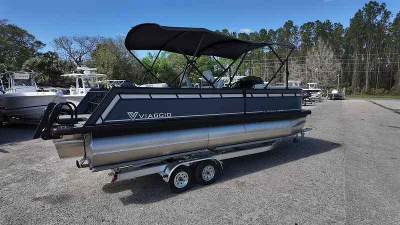 Slide: The Image of 2025 Viaggio X22S pontoon boat on trailer, parked outdoors with trees in background. - 5